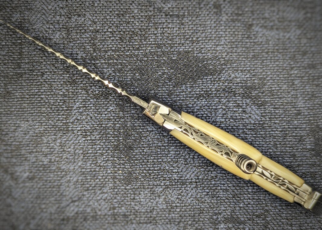 Laguiole Fontenille Pataud avec tire bouchon pointe de corne blonde, ouvert. Vue du dessus sur la guilloche des platines, ressort et lame. Couteau industriel de marque française. Coutellerie française traditionnelle Coutellerie Châteauneuf-du-Pape, Coutellerie du Pape, Vaucluse
