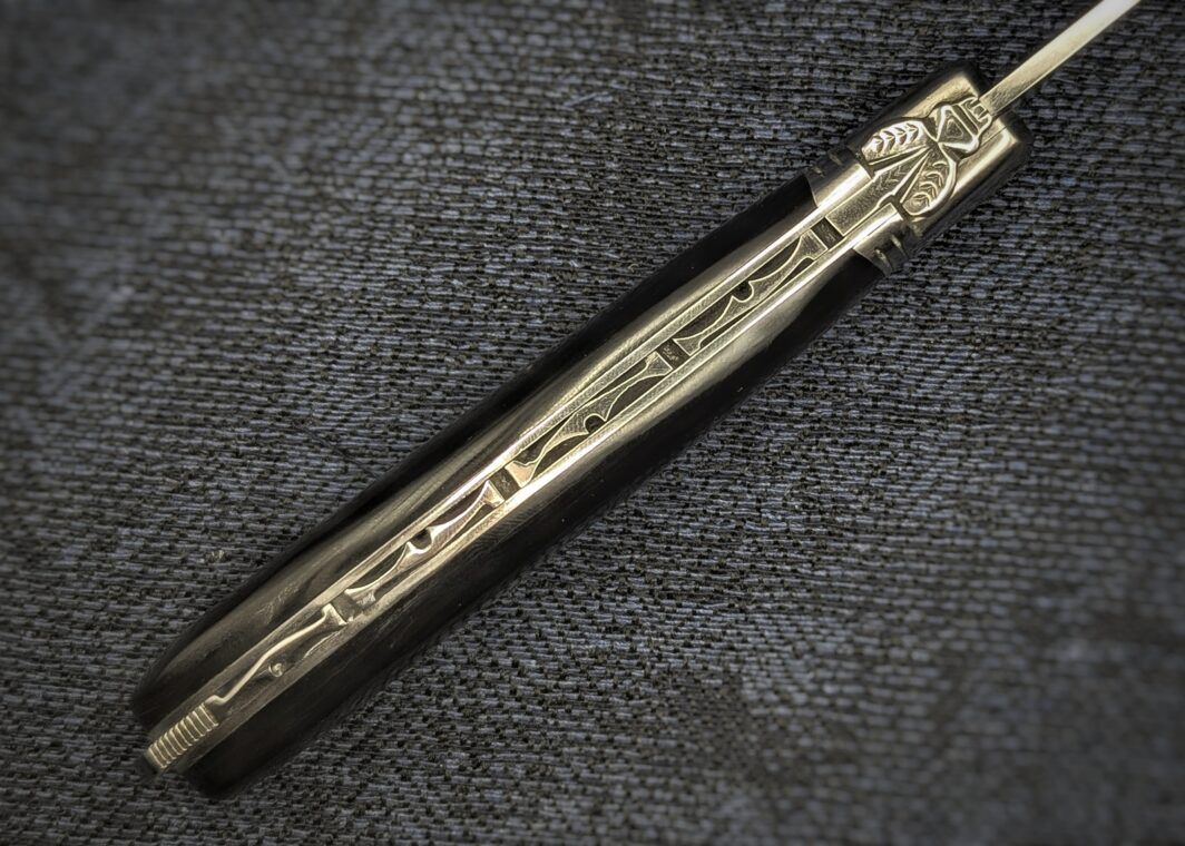 Laguiole Fontenille Pataud Pompe arrière en corne de buffle avec mitre en inox vue du dessus sur le guillochage et l'abeille. Couteau industriel de marque française. Coutellerie française traditionnelle Coutellerie Châteauneuf-du-Pape, Coutellerie du Pape, Vaucluse