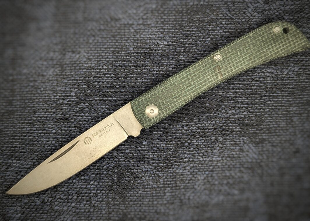 Couteau pliant Scout de Maserin position ouverte. Le manche est en micarta tressé vert. Vue du côté gauche avec le poinçon sur la lame. Couteau industriel de marque italienne Coutellerie Châteauneuf-du-Pape, Coutellerie du Pape, Vaucluse