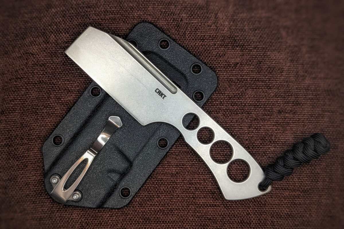 Couteau Razel Chizel de CRKT. Un intégral en acier avec des trous dans le manche. Vue du côté gauche avec le poinçon sur la lame. L'étui avec clip pour la ceinture est en fond. Couteau industriel de marque américaine Coutellerie Châteauneuf-du-Pape, Coutellerie du Pape, Vaucluse