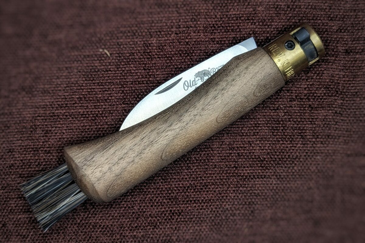 Couteau à champignon OldBear. Manche en noyer. Vue du couteau fermé, on voit le poinçon dépassé. Il y a des poils au bout du manche pour nettoyer les champignons. Couteau industriel de marque italienne Coutellerie Châteauneuf-du-Pape, Coutellerie du Pape, Vaucluse