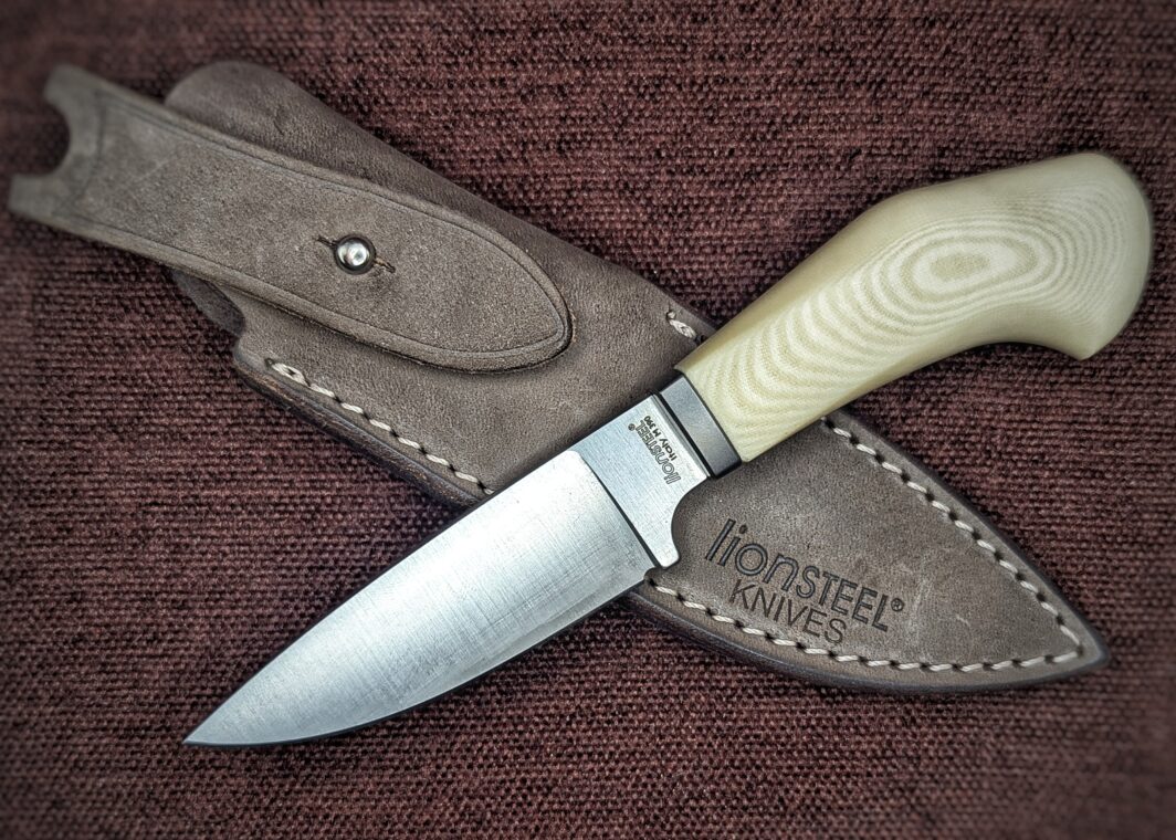 Couteau de chasse Fixe Lionsteel mache en micarta blanc. Vue côté gauche avec étui en cuir. Couteau industriel de chasse de marque italienne Coutellerie Châteauneuf-du-Pape, Coutellerie du Pape, Vaucluse