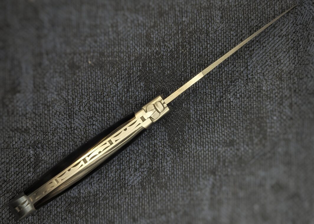 Laguiole Fontenille Pataud pointe de corne noire, ouvert. Vue du dessus sur l'abeille et la guilloche. Couteau industriel de marque française. Coutellerie française traditionnelle Coutellerie Châteauneuf-du-Pape, Coutellerie du Pape, Vaucluse