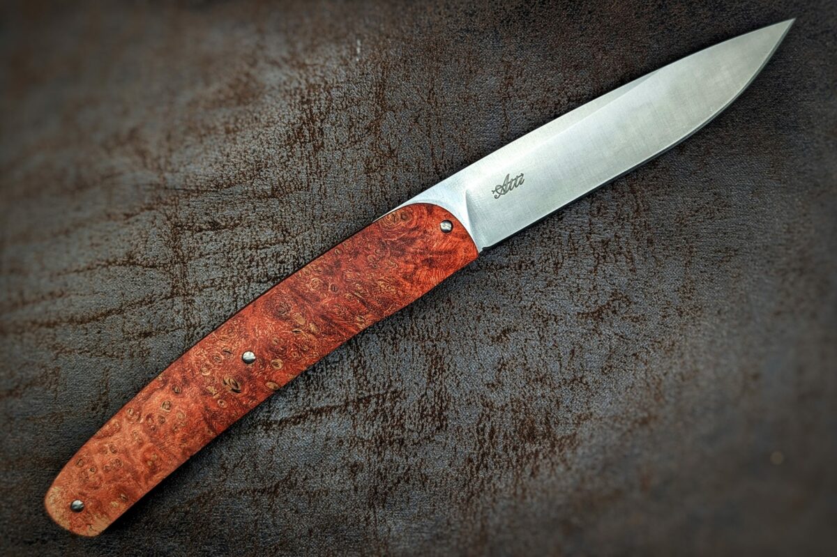 Couteau pliant Gourmet de Maserin. Position ouverte, vue côté droit du couteau. Le manche est en loupe d'érable stabilisée et teintée rouge Couteau industriel de marque italienne Coutellerie Châteauneuf-du-Pape, Coutellerie du Pape, Vaucluse