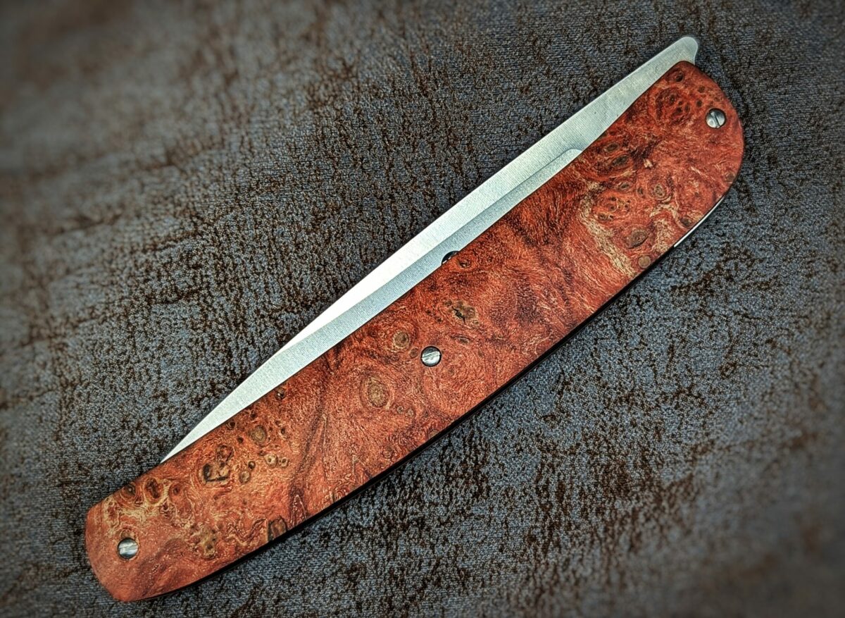 Couteau pliant Gourmet de Maserin. Position fermée, vue côté gauche du couteau. Le manche est en loupe d'érable stabilisée et teintée rouge Couteau industriel de marque italienne Coutellerie Châteauneuf-du-Pape, Coutellerie du Pape, Vaucluse