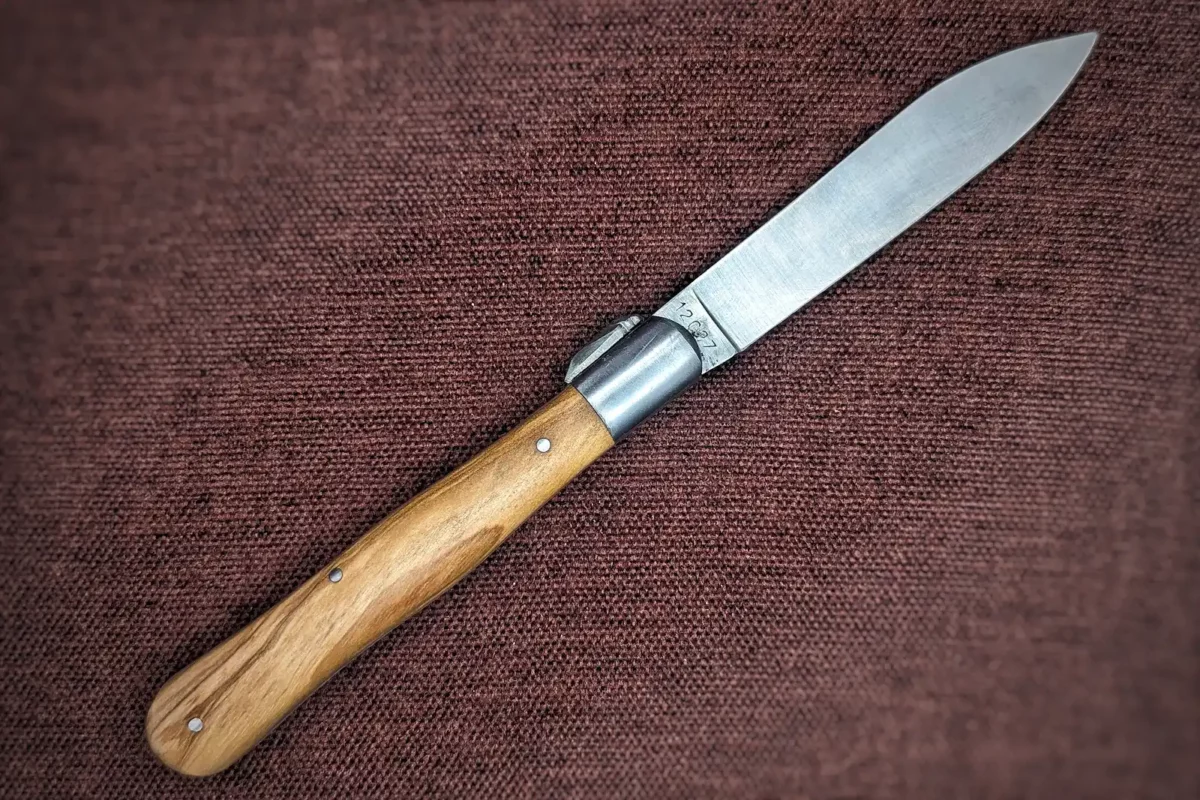 Couteau pliant le Provençal de Au Sabot. Position ouverte, côté droit. Le manche est en olivier. Mitre avant en inox Couteau industriel de marque française Coutellerie Châteauneuf-du-Pape, Coutellerie du Pape, Vaucluse