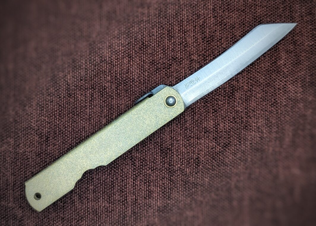 Couteau pliant Higonokami. Position ouverte, côté droit. Une inscription sur la lame. Le manche est en laiton. Couteau industriel de marque japonaise Coutellerie Châteauneuf-du-Pape, Coutellerie du Pape, Vaucluse