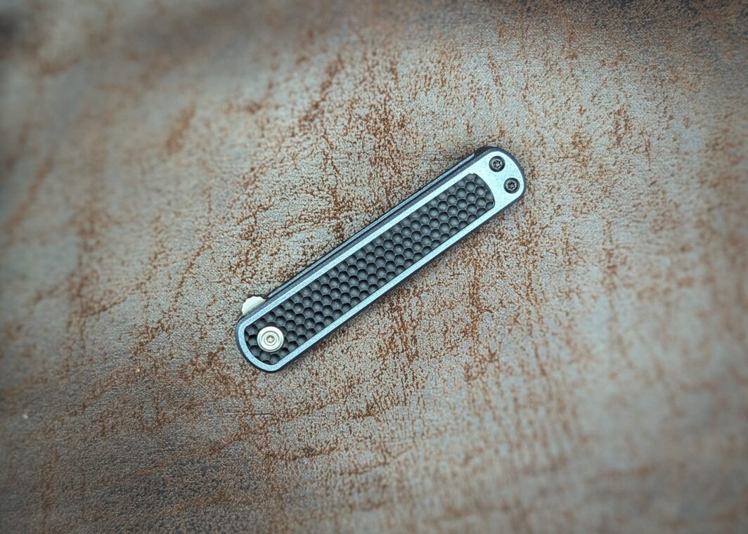 Couteau pliant de CRKT. Position fermé, côté gauche. La lame n'est plus du tout apparente. Le manche est noir avec un liseré bleu tout autour. Couteau industriel de marque américaine Coutellerie Châteauneuf-du-Pape, Coutellerie du Pape, Vaucluse