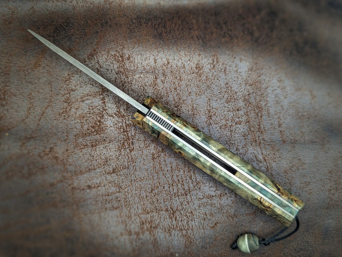 Couteau pliant Liner Lock 'Kiru' de l'artisan Noki. Vue du dessus. Lame en damas 208 couches. Manche en Loupe de peuplier stabilisée teintée vert. Couteau artisanal français à Châteauneuf-du-Pape, Vaucluse Coutellerie du Pape
