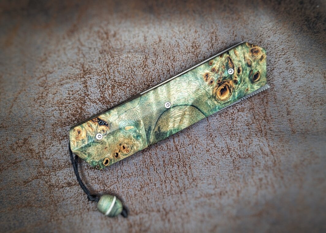 Couteau pliant Liner Lock 'Kiru' de l'artisan Noki. Position fermée, côté droit. Lame en damas 208 couches. Manche en Loupe de peuplier stabilisée teintée vert. Couteau artisanal français à Châteauneuf-du-Pape, Coutellerie du Pape, Vaucluse