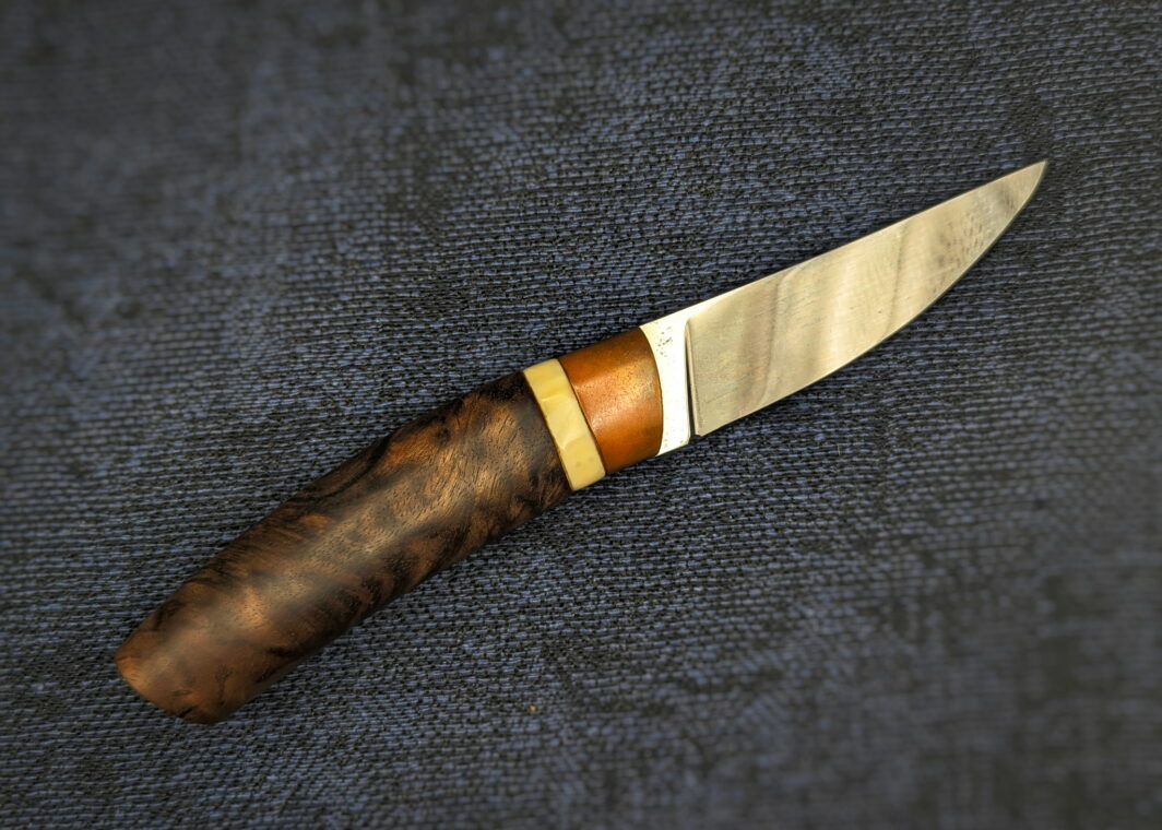 Couteau fixe de l'artisan Lou Marius. Vue du côté droit. La lame est en finition polie. Le manche est en noyer avec une bague en ivoire de phacochère et une autre en bronze cuivré. Couteau artisanal, coutellerie français à Châteauneuf-du-Pape, Vaucluse Coutellerie du Pape