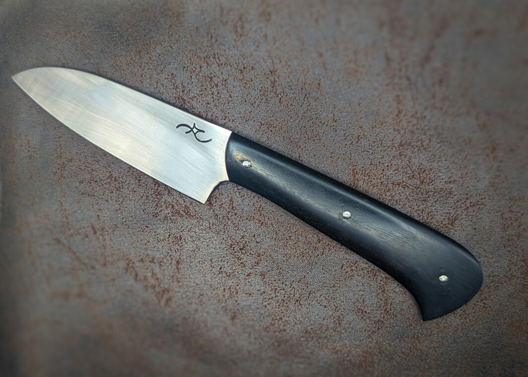 Couteau cuisine L'Office par l'artisan Alban Campagnola. Côté gauche. Le manche est en ébène. La lame est en 14C28N. On y voit le poinçon de l'artisan. Couteau artisanal, coutellerie français à Châteauneuf-du-Pape, Vaucluse Coutellerie du Pape