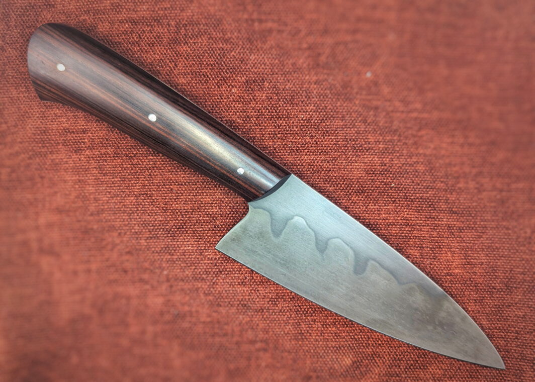 Couteau fixe de cuisine par l'artisan Alban Campagnola. Vue du côté droit. La lame est en XC100 avec une révélation d'une trempe sélective au perchlorure de fer. Le manche est en Palissandre de santos. Couteau artisanal, coutellerie français à Châteauneuf-du-Pape, Vaucluse Coutellerie du Pape