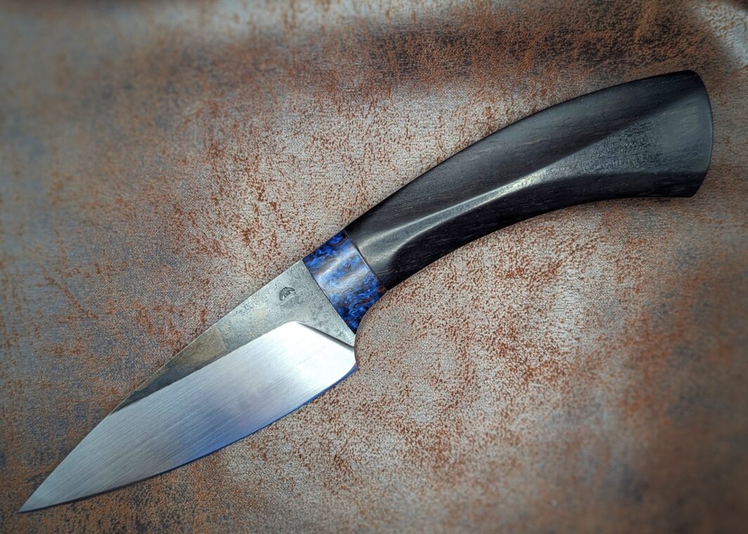Couteau fixe, soie par Lou Marius. Manche en ébène, bague en bouleau stabilisé bleu. Côté gauche