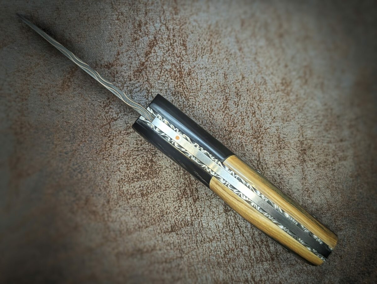 Couteau pliant artisanal par Dahéna Urli. Lame en damas cuivre manche en ivoire de mammouth et corne de buffle. Position ouverte, vue du dessus