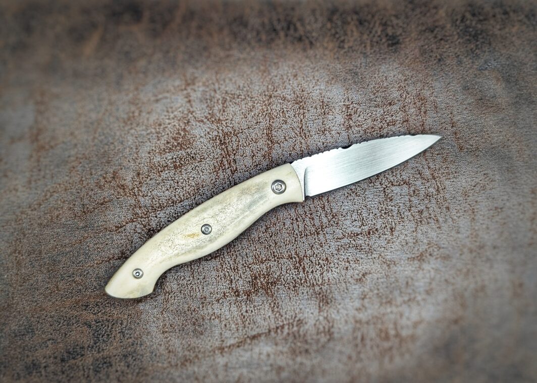 Couteau pliant artisanal par Dahéna Urli. Manche en bois de renne, platines en cuivre et lame en Z40. Position ouverte, côté droit