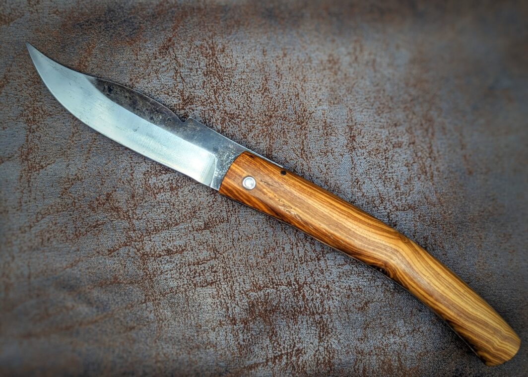 Couteau pliant de poche par José Viale. Manche en Olivier. Lame en carbone XC75. Position ouverte, côté gauche