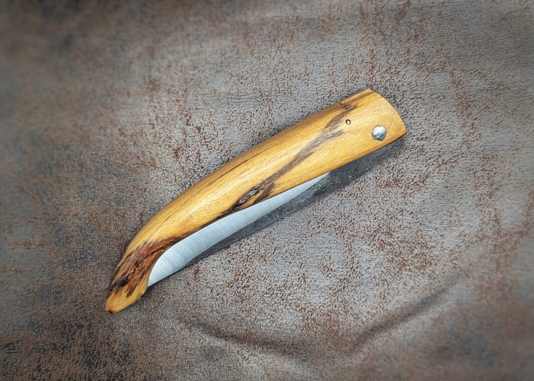 Couteau pliant Capulagui de l'artisan José Viale. Lame en XC75, acier Carbone. Manche en olivier