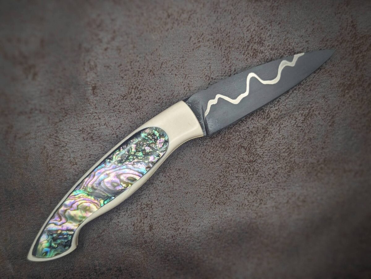 Couteau pliant par l'artisan Dahéna URLI. Lame en acier sandwich carbone, manche en ivoire de mammouth et abalone. Position ouvert, côté droit