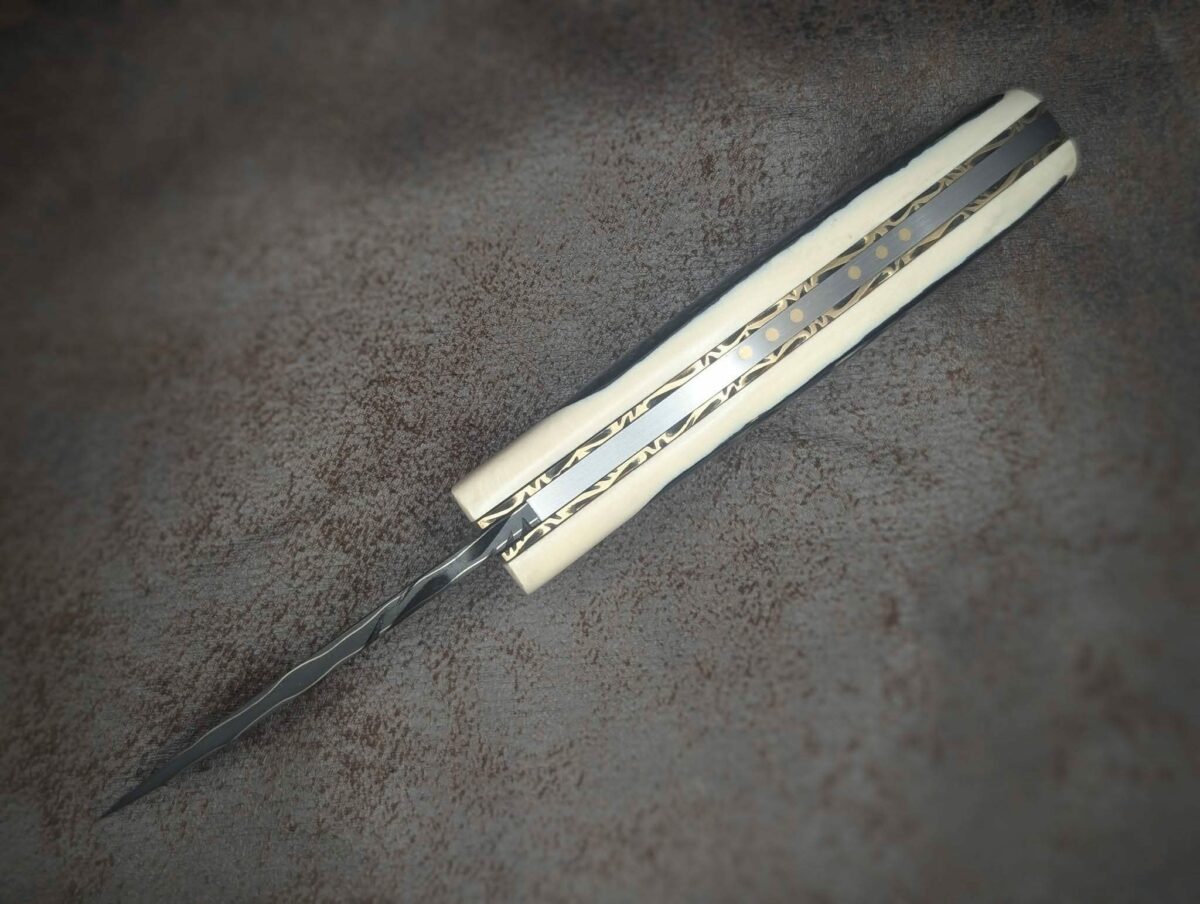 Couteau pliant par l'artisan Dahéna URLI. Lame en acier sandwich carbone, manche en ivoire de mammouth et abalone. Position ouvert, vue du dessus