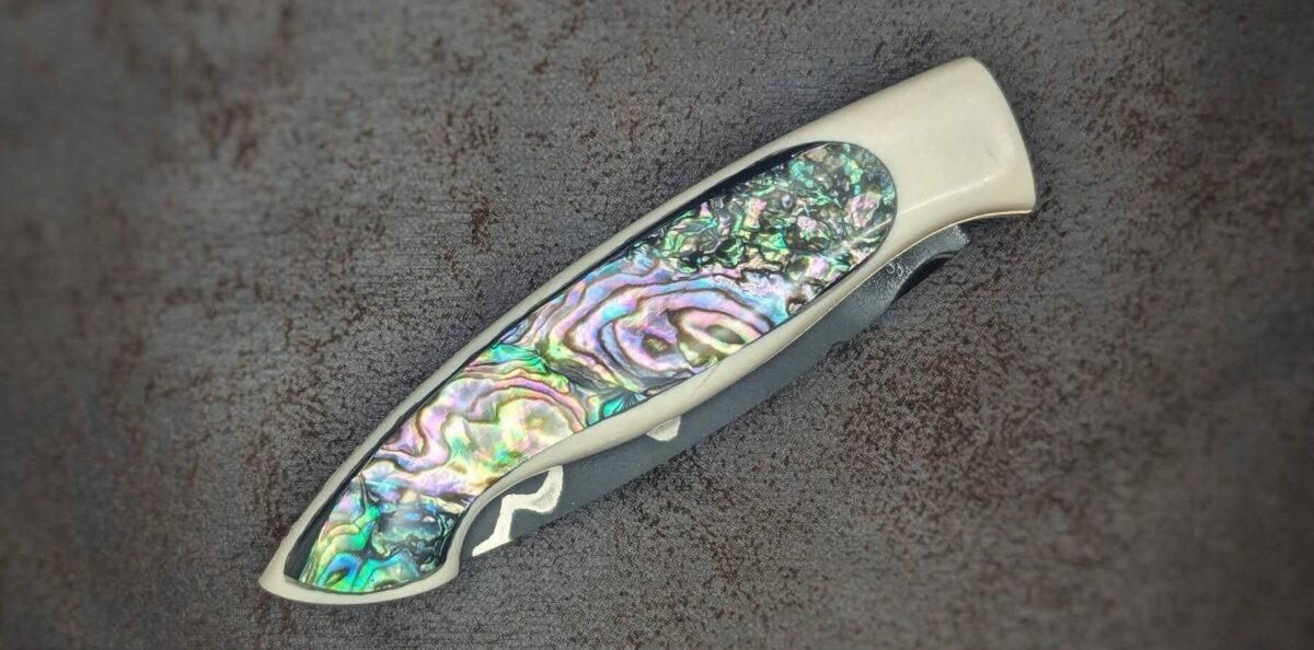 Couteau pliant par l'artisan Dahéna URLI. Lame en acier sandwich carbone, manche en ivoire de mammouth et abalone. Position fermé, côté droit