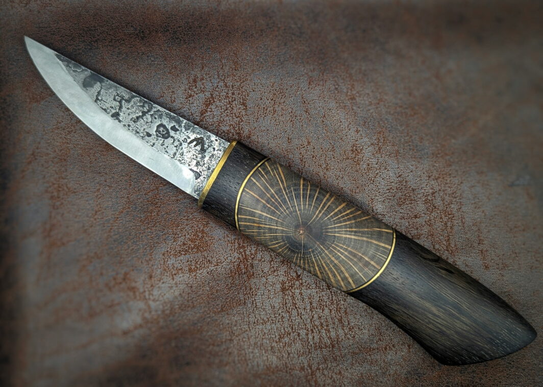 Couteau fixe puukko artisanal forgé par Tête d'Enclume. 'Shai Hulud' lame en 80CRV2 et manche enMorta, Laiton et Chêne en bois debout. Côté gauche