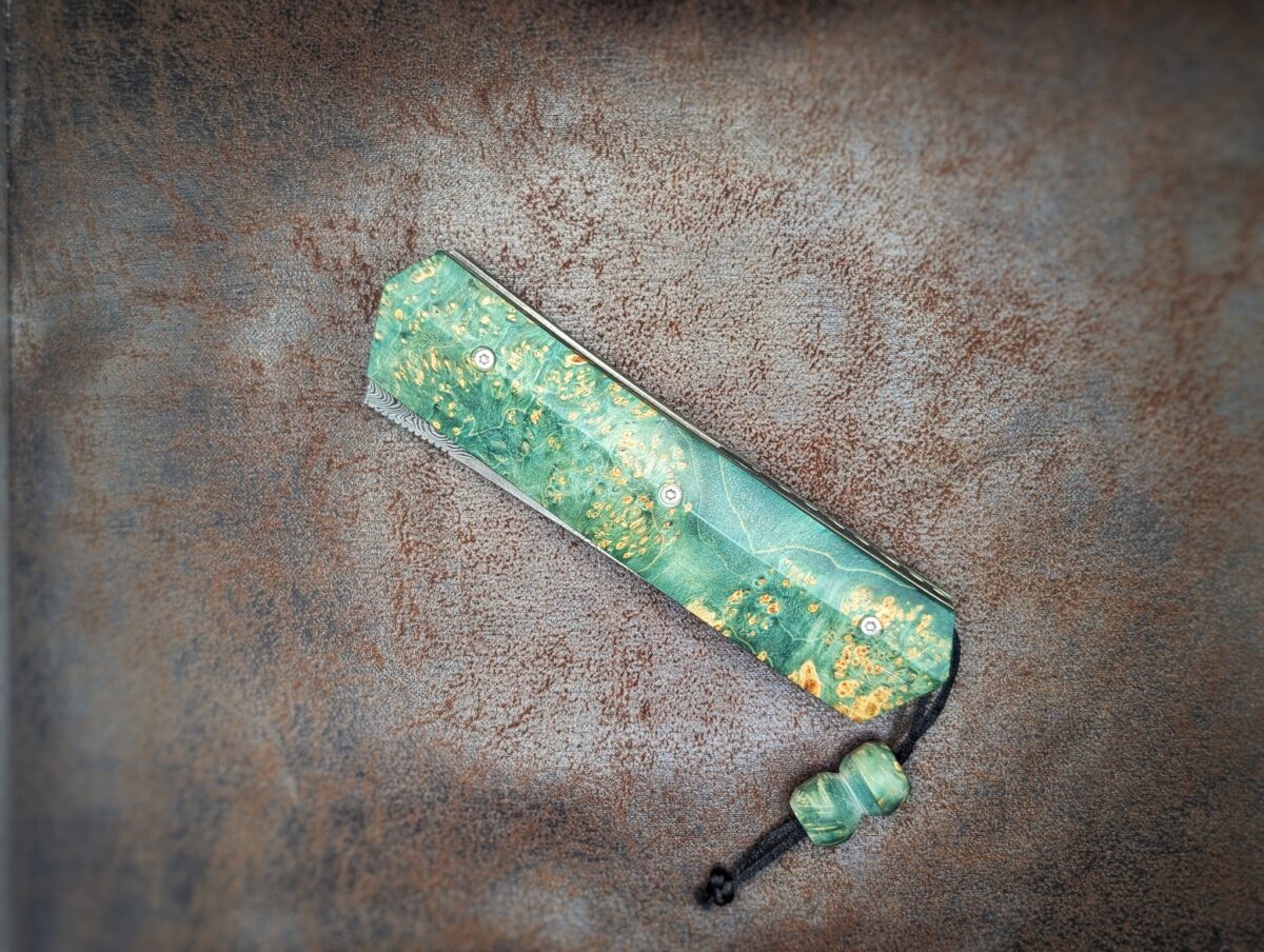 Couteau pliant Liner Lock 'Kiru' de l'artisan Noki. Position fermée, côté gauche. Lame en damas 208 couches. Avec étui en cuir noir. Couteau artisanal français à Châteauneuf-du-Pape, Vaucluse Coutellerie du Pape