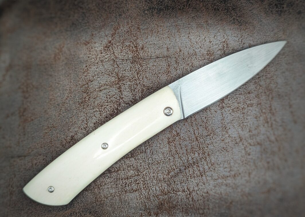 Couteau piémontais artisanal par Dahéna URLI. Lame en inox Z40 et manche en os de chameau. Platines en laiton. Position ouvert, vue du côté droit