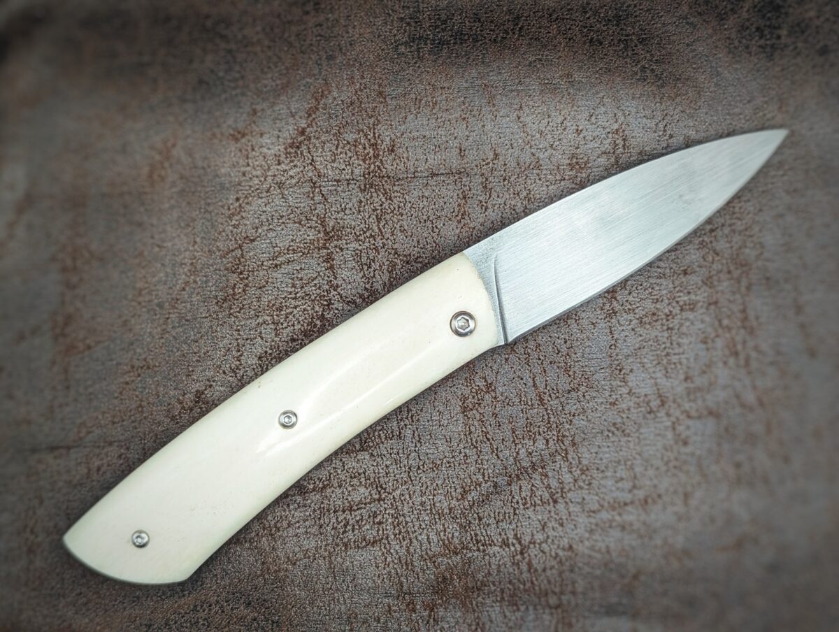 Couteau piémontais artisanal par Dahéna URLI. Lame en inox Z40 et manche en os de chameau. Platines en laiton. Position ouvert, vue du côté droit
