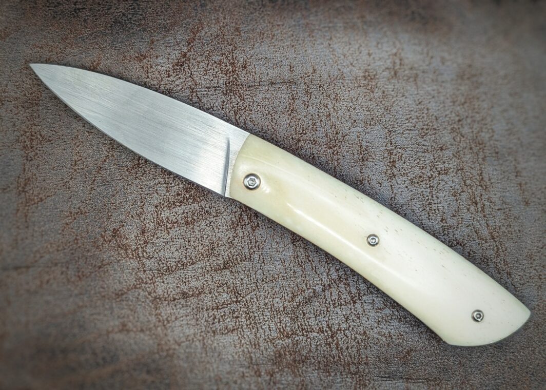 Couteau piémontais artisanal par Dahéna URLI. Lame en inox Z40 et manche en os de chameau. Platines en laiton. Position ouvert, vue du côté gauche